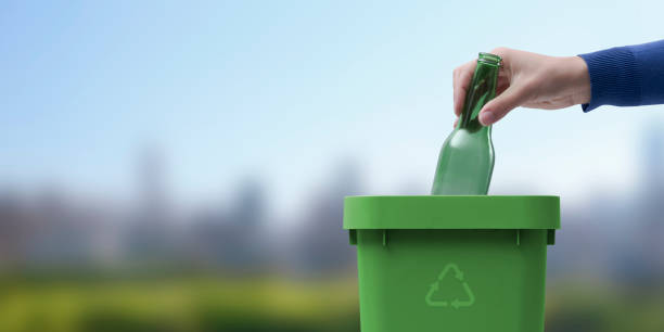 Woman putting a glass bottle in the trash bin stock photo