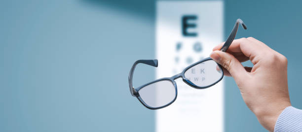 Optometrist holding glasses and eye chart stock photo