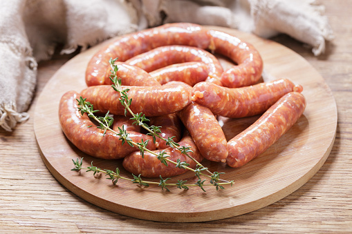 Fresh sausages on a chopping board on wooden table