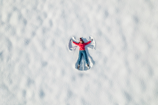 Mature woman having fun lying in snow, Austria