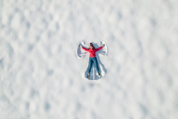 Woman lying on a snow and doing angel print on a snow covered land. Aerial, top view. Drone photo. Winter stock photo