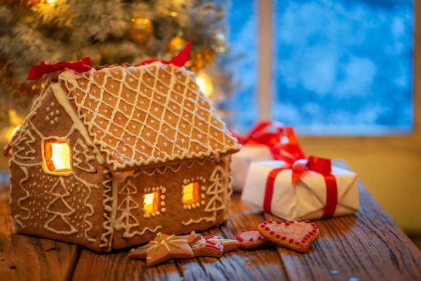 istock Gingerbread cottage and presents under Christmas tree with light. 1426857658