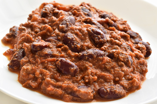 Traditional Mexican food.  Chilli con carne with ground beef, chillies, onion and red kidney beans on a plate.