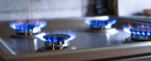 Photo of Close-up of a blue fire from a kitchen stove. 4 gas burners with a burning flame. economy concept. wide banner