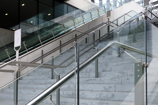 Concrete staircases with silver metallic handrails and escalators lining side by side.