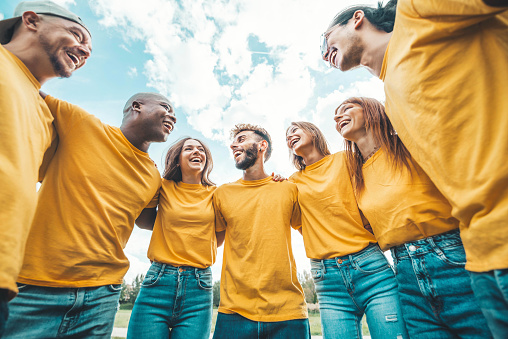 Multi ethnic young people team hugging together outside - International community of students support and help each other - Friendship, team building and diversity concept