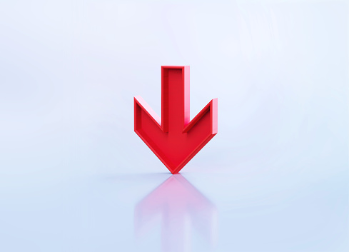 Red down arrow symbol sitting over grey reflective background. Horizontal composition with copy space.