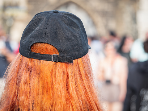 Prague, Czech Republic - June 2022:  Rear view of a redhead woman wearing a black hat.