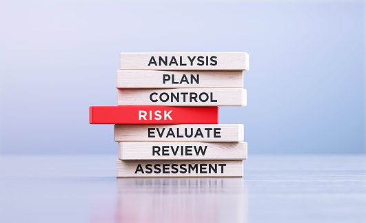 Risk management related words written wood blocks sitting on a wood surface in front of a defocused background. Risk management concept.