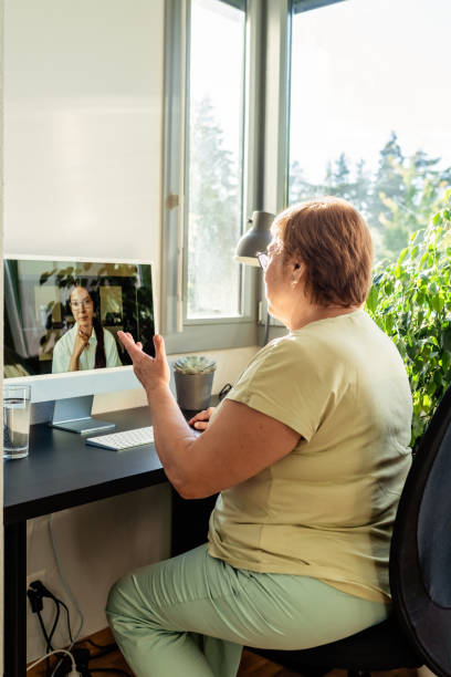Senior adult plus size woman having online consulting session with professional psychologist or nutritionist using computer at home. Digital service business stock photo