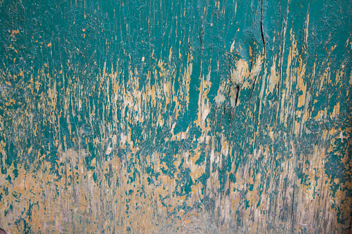 green painted wooden wall. the paint has peeled off. the paint is cracked. peeled off and faded