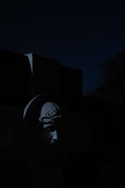 istock Jesus Christ bust head on cemetery tomb stone sculpture object soft focus vertical photography on Halloween eve time at night with dark background 1426883188