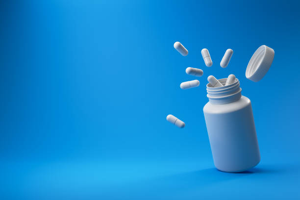 istock White pills and plastic medical container on a blue background. 1426889652