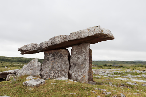 Poulnabrone dolmen (Poll na Brón in Irish is an unusually large dolmen or portal tomb located in the Burren, County Clare, Ireland. Situated on one of the most desolate and highest points of the region, it comprises three standing portal stones supporting a heavy horizontal capstone, and dates to the Neolithic period, probably between 4200 BC and 2900 BC. It is the best known and most widely photographed of the approximately 172 dolmens in Ireland. 
The karst setting has been formed from limestone laid down around 350 million years ago. The dolmen was built by Neolithic farmers, who chose the location either for ritual, as a territorial marker, or as a collective burial site. What remains today is only the 