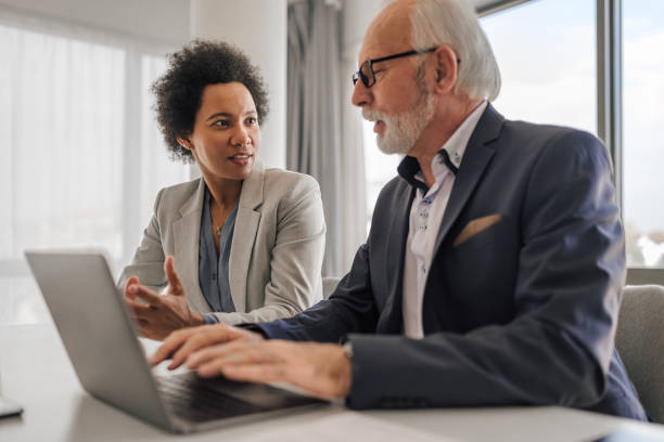 Hardworking senior businessman, consulting with his coworker about the company project. Helpful african-american company employee, working with her senior colleague on a company project. working seniors stock pictures, royalty-free photos & images