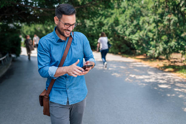 istock Delighted young adult businessman, getting a notification on his phone, while walking. 1426897461