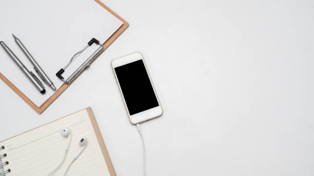istock Mobile phone with head phone,wood board document and blank diary top view copy space 1426904353