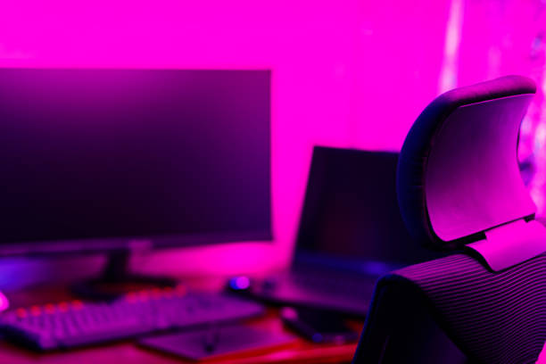 istock Creative designer's workplace, back view. Office chair and work desk view with graphic tablet, computer and smartphone. Retoucher home office in neon pink blue 1426906222