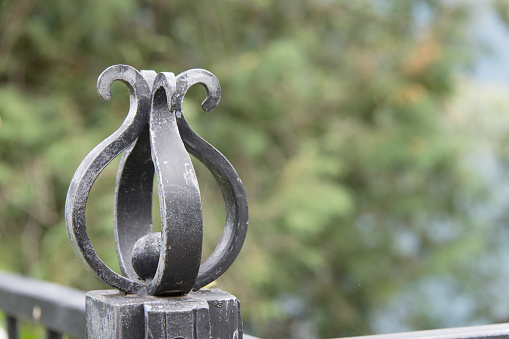 Close up of ornate wrought iron forged steel railing termination in the form of a curved flower as a concept for metalworking locksmithing and craftsmanship