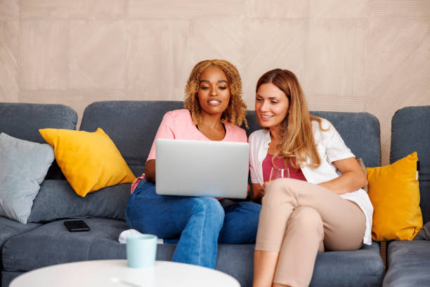 istock Female friends using laptop computer while spending leisure time at home 1426911134