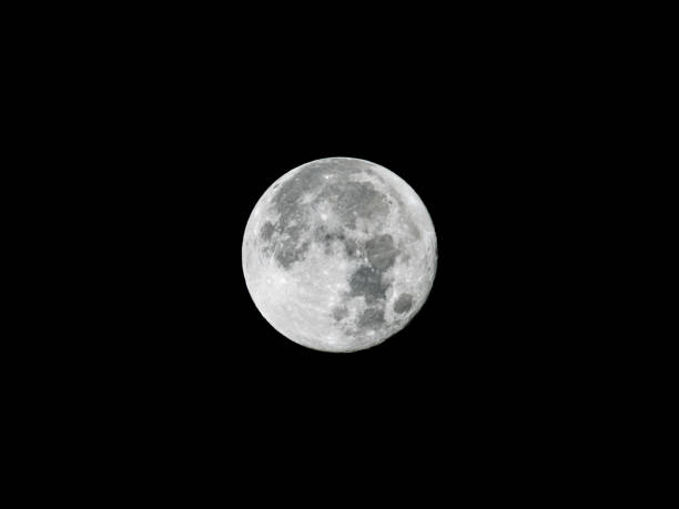 Full moon on the black night sky shining bright. The surface structure is visible of the Earth's natural satellite. Craters caused by impacts are observable. A detailed close-up from Germany.