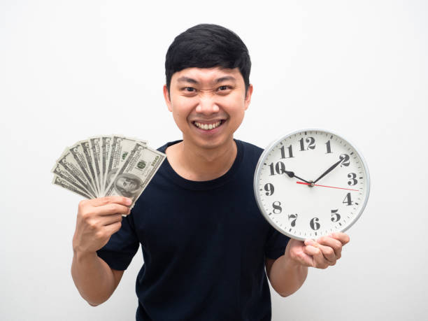 homem retrato segurando um monte de dinheiro com relógio analógico na mão sorriso felicidade - clock wall clock face clock hand - fotografias e filmes do acervo