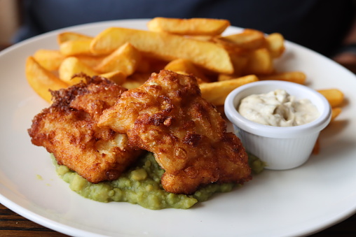 A plate of traditional British fish,chips and mushy peas with tartar sauce.