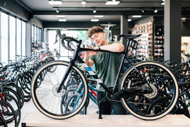 バイクショップで新しい自転車でチェックアウトする若い男性 - bicycle shop ストックフォトと画像