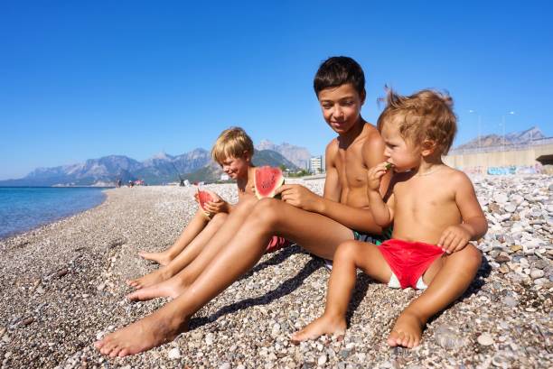 istock Two brothers eat a watermelon on the beach. 1426924329