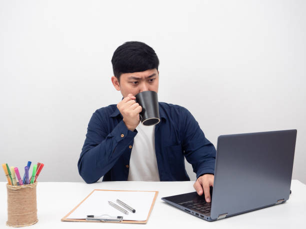 istock Man sitting at office workplace drinking coffee with using laptop for working 1426925403
