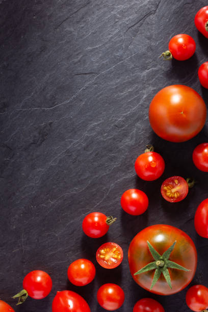 istock Fresh tomato on black slate background table. Tomatoes on tabletop 1426926899