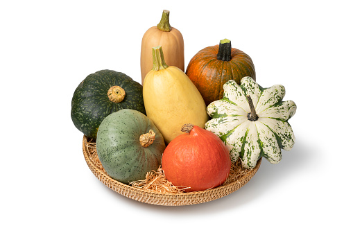 Basket with a variation of autumn pumpkins isolated on white background