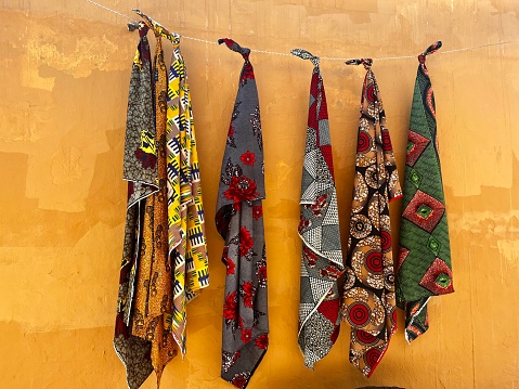 Colourful African batik fabric display against a yellow wall