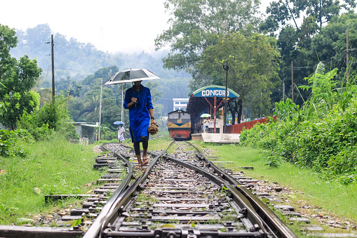 Man walking on the railway on a rainy day. He has an umbrella in his hand. Man with an umbrella on the railway, waiting for new adventures and travel.