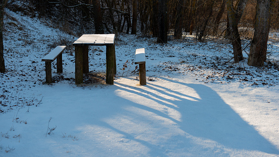Tables and benches in the forest are covered with snow. January. Web banner. Ukraine.