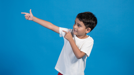 happy child with blue background, pointing with finger