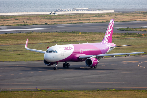 Osaka, Japan  - August 14, 2022 : A Peach Aviation Airbus A320 prepares to take off from Kansai International Airport in Osaka Prefecture, western Japan.