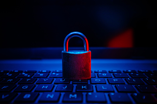 Locked padlock on a laptop keyboard, with blue lighting. 
Internet security
