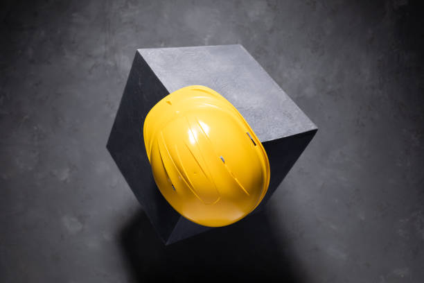 istock Concrete cube and construction helmet on floor background texture. Cement block and hardhat 1426955834