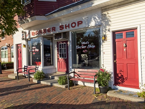 Barbershop on Main street in North Andover Massachusetts, September 2022. A stereotypical barbershop on main street USA integrated along a tree lined brick sidewalk and coexisting with multi family residences. The Mal's barbershop has been in business since 1977.