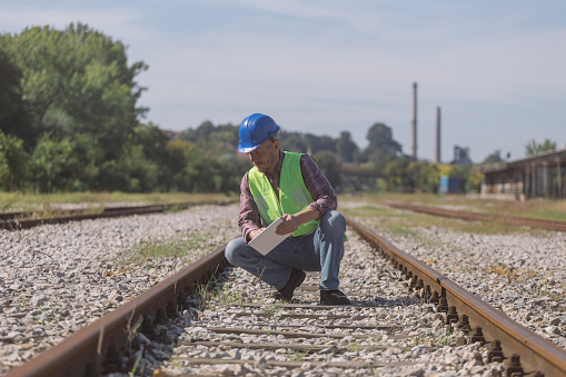 Engineer inspecting some railroad tracks using digital tablet