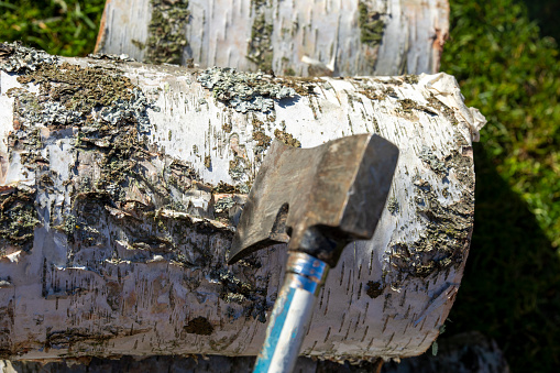 Chopped wood for a wood burner on a domestic garden patio with a chopping axe.