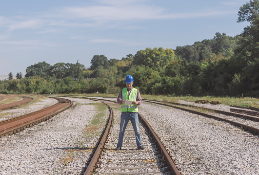 Engineer inspecting some railroad tracks using digital tablet