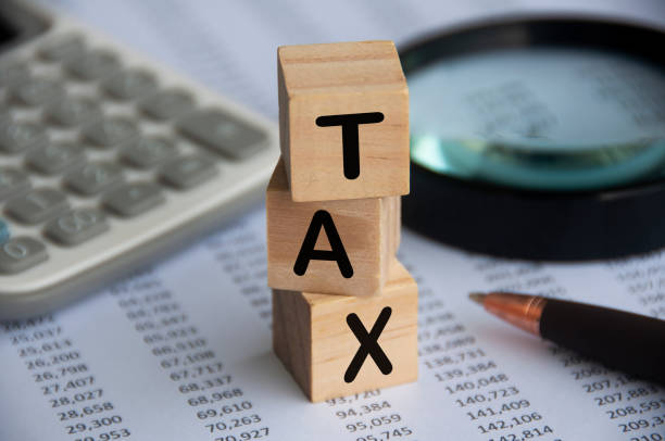 電卓、ペン、虫眼鏡、データ分析の背景を持つ木製ブロックに税金の言葉。税コンセプト - tax collection ストックフォトと画像