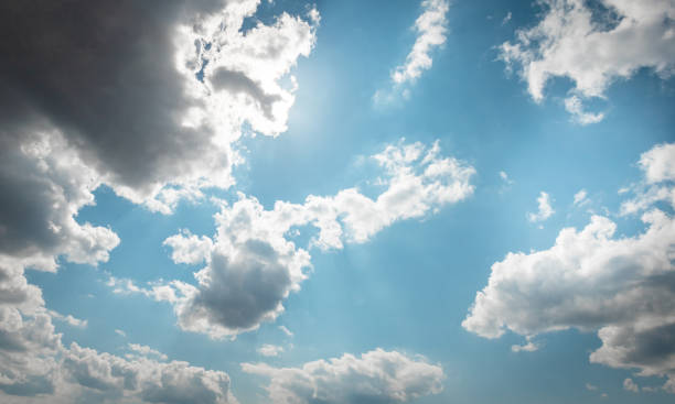 istock DAY SKY WITH BLUE AND WHITE CLOUDS and sun beam behind 1426966324