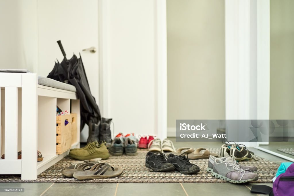 Shoes scattered on door mat at home Different types of shoes scattered on door mat at home Corridor Stock Photo