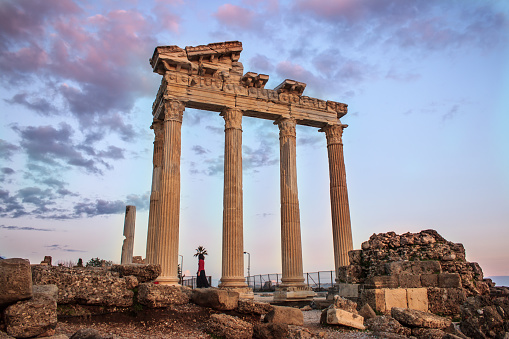 Historical ancient Apollon Temple in the evening landscape with dramatic purple cloudy sky in Side, Antalya, Turkey.
