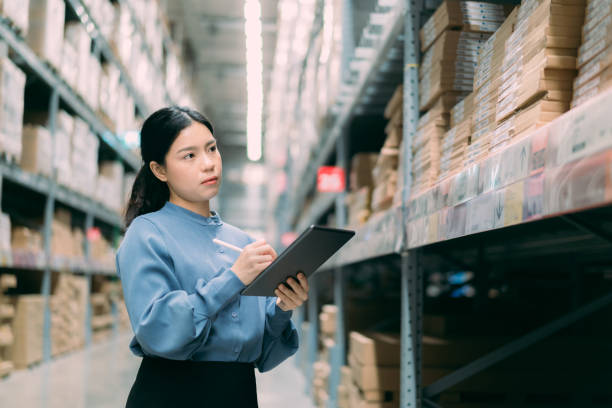 istock Young smart Asian business working woman thinking while using digital tablet to check goods on shelves for product management  in warehouse, Logistics business planning concept with copy space 1426970160