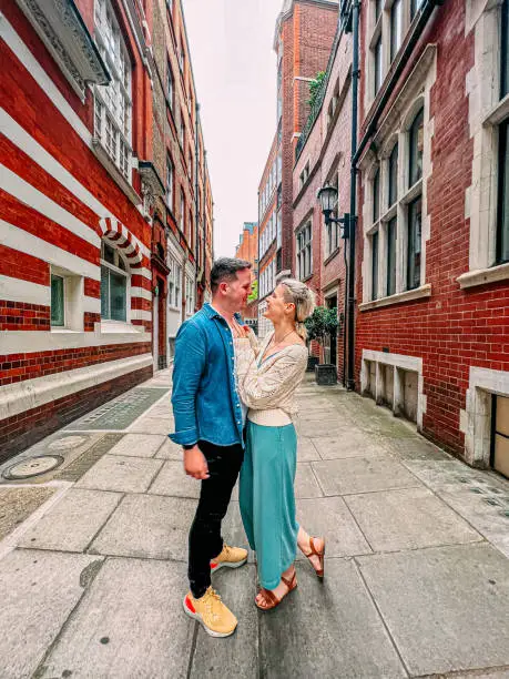 Candid Portrait of a Cute Caucasian Male and Female Standing and Smiling Together While on Vacation in a Vibrant-Colored Alley in London, England