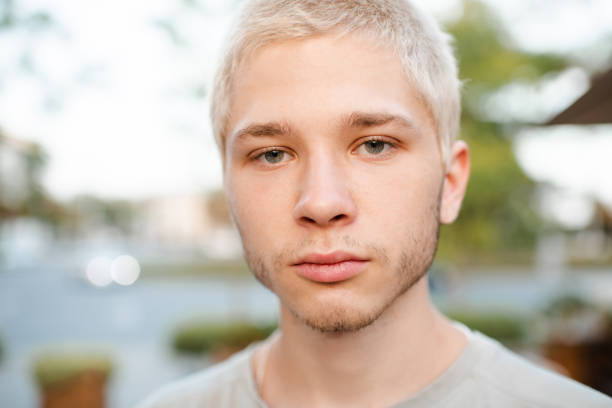 Portrait of young man outdoor looking at camera, background with copy space, full frame vertical composition